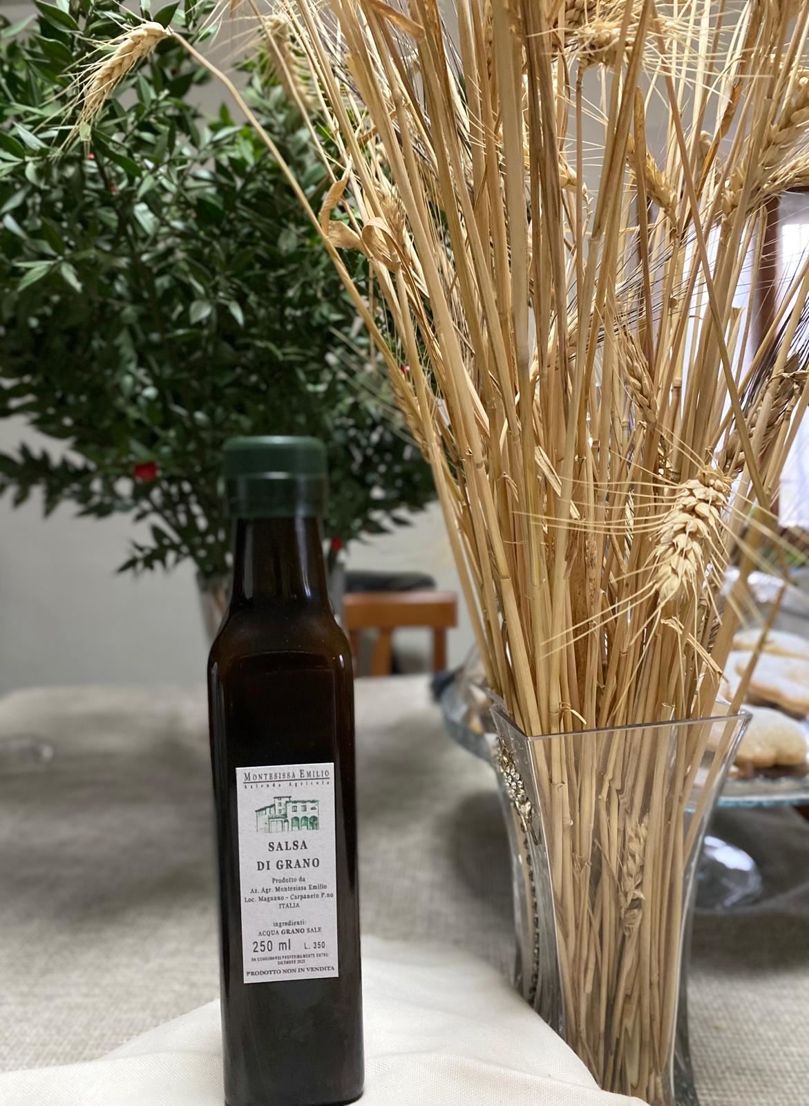 Una bottiglia di salsa di grano accanto alle spighe