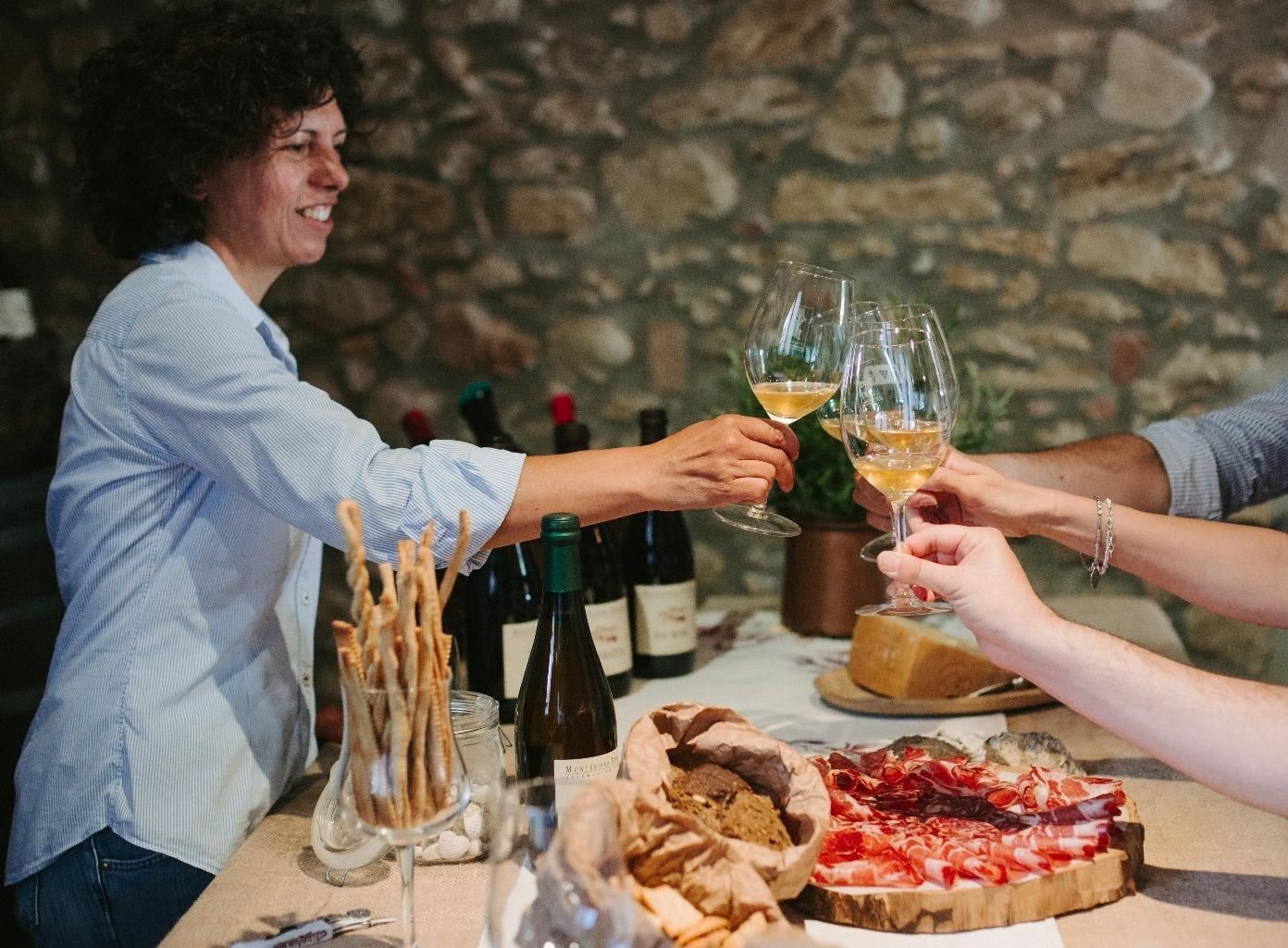 Brindisi con i calici durante una degustazione con taglieri in cantina